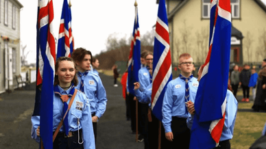 Formal line of Icelandic scouts in blue uniforms holding national flags