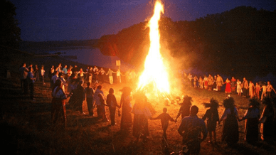 Люди водять хороводи навколо великого вогнища