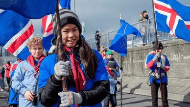 Young scouts smiling and carrying Icelandic flags