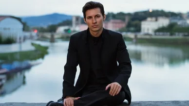 Pavel Dourov assis près d’une rivière, vêtu de noir, regard calme et posé.