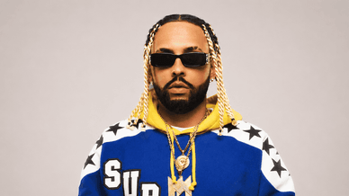 Retrato de Mizzy Miles com um casaco azul e amarelo da Supreme com estrelas e correntes douradas