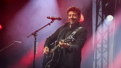 Patrick Bruel jouant de la guitare sur scène pendant un concert.