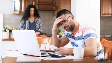 Homme préoccupé devant un ordinateur en pensant au recouvrement amiable des créances.