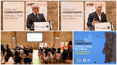 Dois oradores num púlpito, sala de apresentação cheia e mapa de Portugal com o percurso da Volta ao Conhecimento