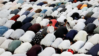 طفل صغير يقف وسط صفوف المصلين الساجدين أثناء أداء صلاة العيد.