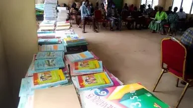 Piles de manuels et fournitures lors de la cérémonie où 45 élèves parrainés par la coopération Évreux-Djougou reçoivent des kits scolaires.