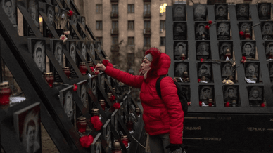 Людина, яка вшановує пам'ять Героїв Небесної Сотні, запалюючи лампадки біля меморіального стенда