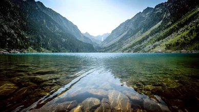Le Lac de Gaube entouré de montagnes verdoyantes et roches.