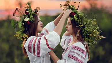 Дівчата поправляють одна одній вінки з польових квітів та трав