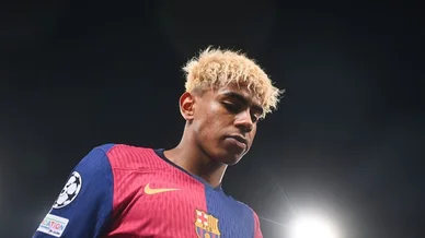 لاعب كرة القدم لامين يامال يرتدي قميص نادي برشلونة مع شعار دوري أبطال أوروبا تحت أضواء الملعب.