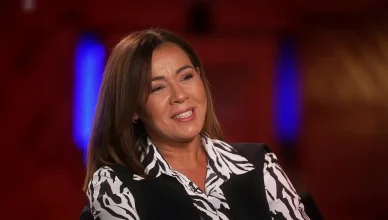 Chimène Badi souriante en chemisier à motifs zébrés lors d’une interview.