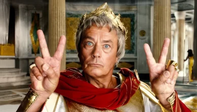 Alain Delon en Jules César levant les doigts en signe de victoire.