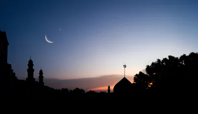 هلال شهر ذي الحجة يظهر في السماء مع ظل لمسجد وقت الغسق.