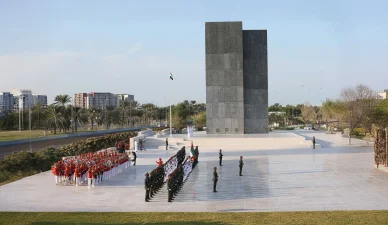 مراسم اصطفاف لفرقة عسكرية وحرس الشرف في ساحة واسعة أمام نصب تذكاري رمادي ضخم في دولة الإمارات.