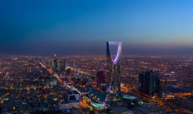 أفق مدينة الرياض ليلاً مع إضاءة برج المملكة المميزة في السعودية.