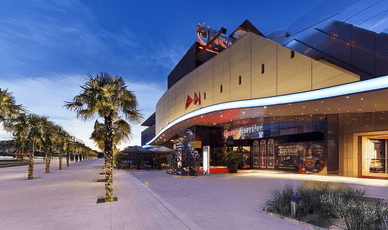 Entrée élégante du Casino Barrière Bordeaux, illuminée de nuit, avec des palmiers décoratifs.