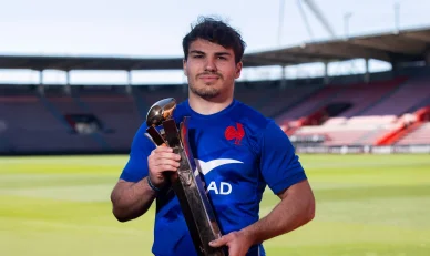 Antoine Dupont tenant un trophée avec le maillot de l’équipe de France.
