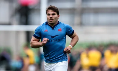 Antoine Dupont courant sur le terrain en maillot bleu.