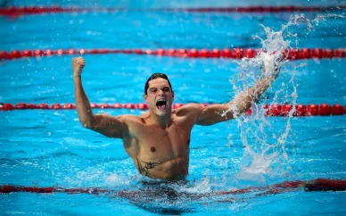 Florent Manaudou célèbre dans la piscine après sa course. Florent Manaudou exprime sa joie après une victoire en natation.