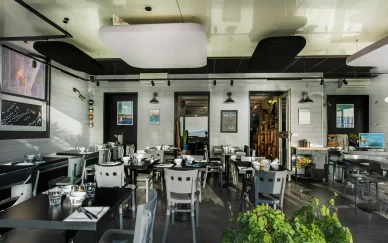 Intérieur de Triskell avec tables et lumière naturelle. Salle contemporaine de la Crêperie Triskell.