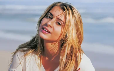 Julie Zenatti posant sur la plage avec les cheveux au vent.