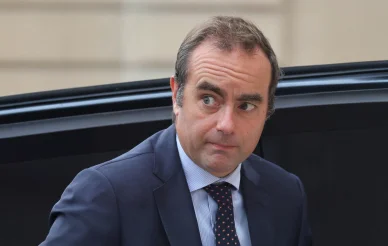 Sébastien Lecornu entre dans un bâtiment gouvernemental. Sébastien Lecornu arrivant à un rendez-vous officiel en costume sombre.