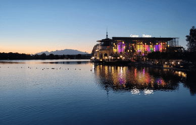 Vue nocturne du Casino Barrière Enghien-les-Bains, avec des lumières colorées se reflétant sur le lac.