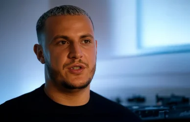 DJ Snake : Créativité au cœur du studio. DJ Snake concentré dans une studio d'enregistrement avec un fond bleu clair.