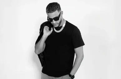 DJ Snake : Style intemporel en noir et blanc. DJ Snake en noir et blanc, portant une chaîne et une veste sur l'épaule.
