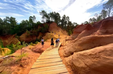Balade sur les sentiers aménagés du Sentier des Ocres dans le Luberon. Promeneurs sur les passerelles en bois du Sentier des Ocres à Roussillon.