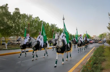 استعراض الفرسان السعوديين في احتفال وطني استعراض فرسان سعوديين بالزي التقليدي يحملون الأعلام الخضراء على خيول احتفالية بالشارع.