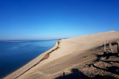 Dune du Pilat longeant l’océan Atlantique sous un ciel bleu clair.