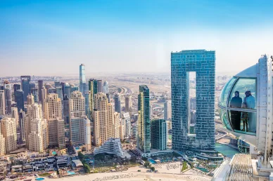 عائلة تنظر من كابينة عجلة عين دبي الزجاجية إلى أفق ناطحات السحاب في جي بي آر وفندق أدرس بيتش ريزورت.
