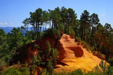 Paysage du Sentier des Ocres entre forêts et falaises colorées. Sommet boisé et relief ocre du Sentier des Ocres à Roussillon.