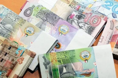 رزم متعددة من الأوراق النقدية للدينار الكويتي بمختلف الفئات مربوطة بأشرطة ورقية.
