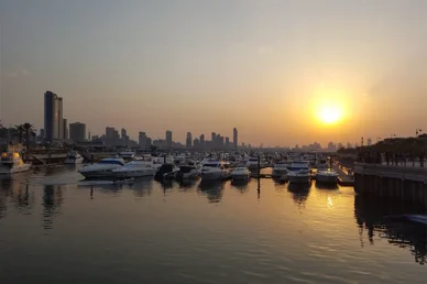 مشهد جميل لمارينا اليخوت وقت الغروب مع أفق لمدينة حديثة في الخلفية.