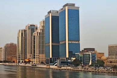 أبراج نايل سيتي ذات الواجهات الزجاجية الزرقاء ومبانٍ حديثة أخرى تطل على ضفاف نهر النيل في القاهرة.