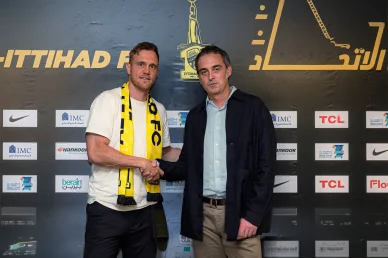 رسمياً في جدة: رايكوفيتش يصافح إدارة الاتحاد لتبدأ رحلته مع النمور الحارس الصربي بريدراغ رايكوفيتش يصافح أحد مسؤولي نادي الاتحاد السعودي أمام لوحة الرعاة الرسميين بعد إتمام التعاقد
