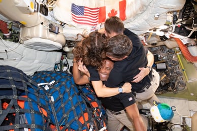 The crew in a group hug with "Rise" floating nearby. 