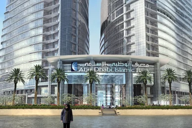 واجهة زجاجية مزدوجة لمبنى مصرف أبوظبي الإسلامي (ADIB) تحمل اسم المصرف وعلامته البارزة، يطل المبنى على مسطح مائي وتزينه أشجار النخيل في الواجهة الأمامية.