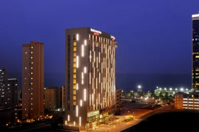 منظر ليلي لمبنى فندق ريزيدينس إن من ماريوت بواجهة مضيئة وإطلالة بحرية.