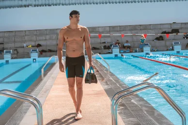 Florent Manaudou prêt pour l’entraînement dans la piscine. Florent Manaudou au bord d’une piscine avec son équipement de natation.