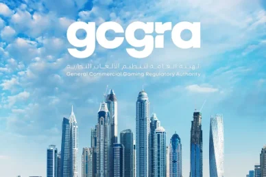 الهيئة العامة لتنظيم الألعاب التجارية (GCGRA) في دولة الإمارات شعار الهيئة العامة لتنظيم الألعاب التجارية (GCGRA) يظهر باللون الأبيض في سماء زرقاء مليئة بالغيوم فوق أفق ناطحات السحاب الحديثة في دبي.