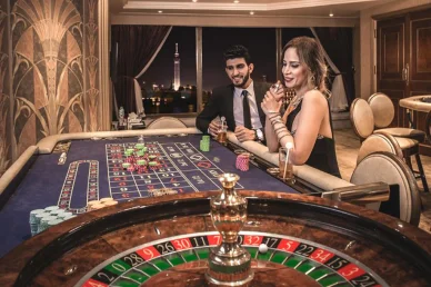 زوجان أنيقان يلعبان الروليت في كازينو فاخر ليلاً مع إطلالة على برج القاهرة المضاء من النافذة