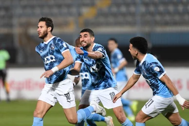 احتفال لاعبي بيراميدز: فرحة عارمة وحماس بعد تسجيل الهدف ثلاثة لاعبين من فريق بيراميدز بقمصان زرقاء يحتفلون بحماس بتسجيل هدف على أرض الملعب، حيث يركض أحدهم ويقوم زميله بجذبه من قميصه بفرح