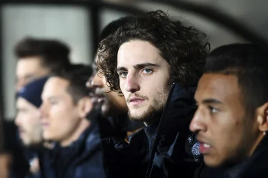 Adrien Rabiot observant un match depuis le banc du PSG. Adrien Rabiot sur le banc de touche avec ses coéquipiers.