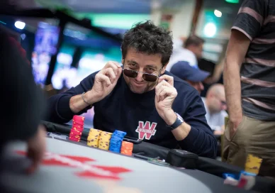Patrick Bruel jouant au poker, lunettes de soleil à la main.