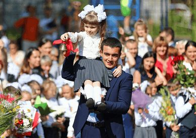 Старшокласник несе на плечі першокласницю