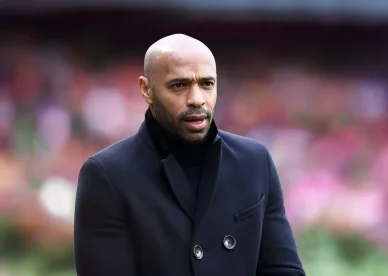 Thierry Henry en costume sombre lors d’un match en tant que consultant.