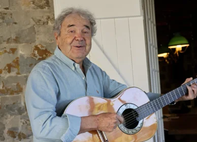 Pierre Perret chanteur et guitariste. Pierre Perret jouant de la guitare.
